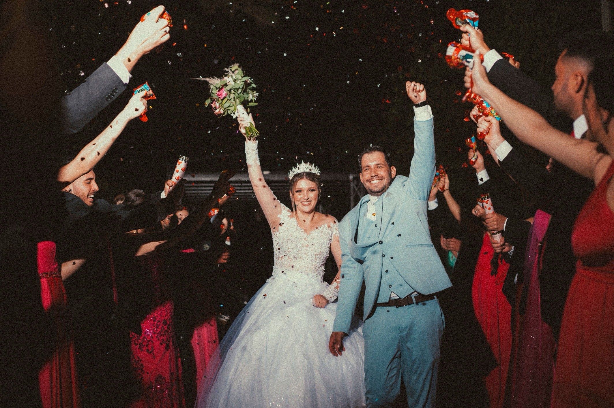 Newlyweds cheering through a confetti send-off at night