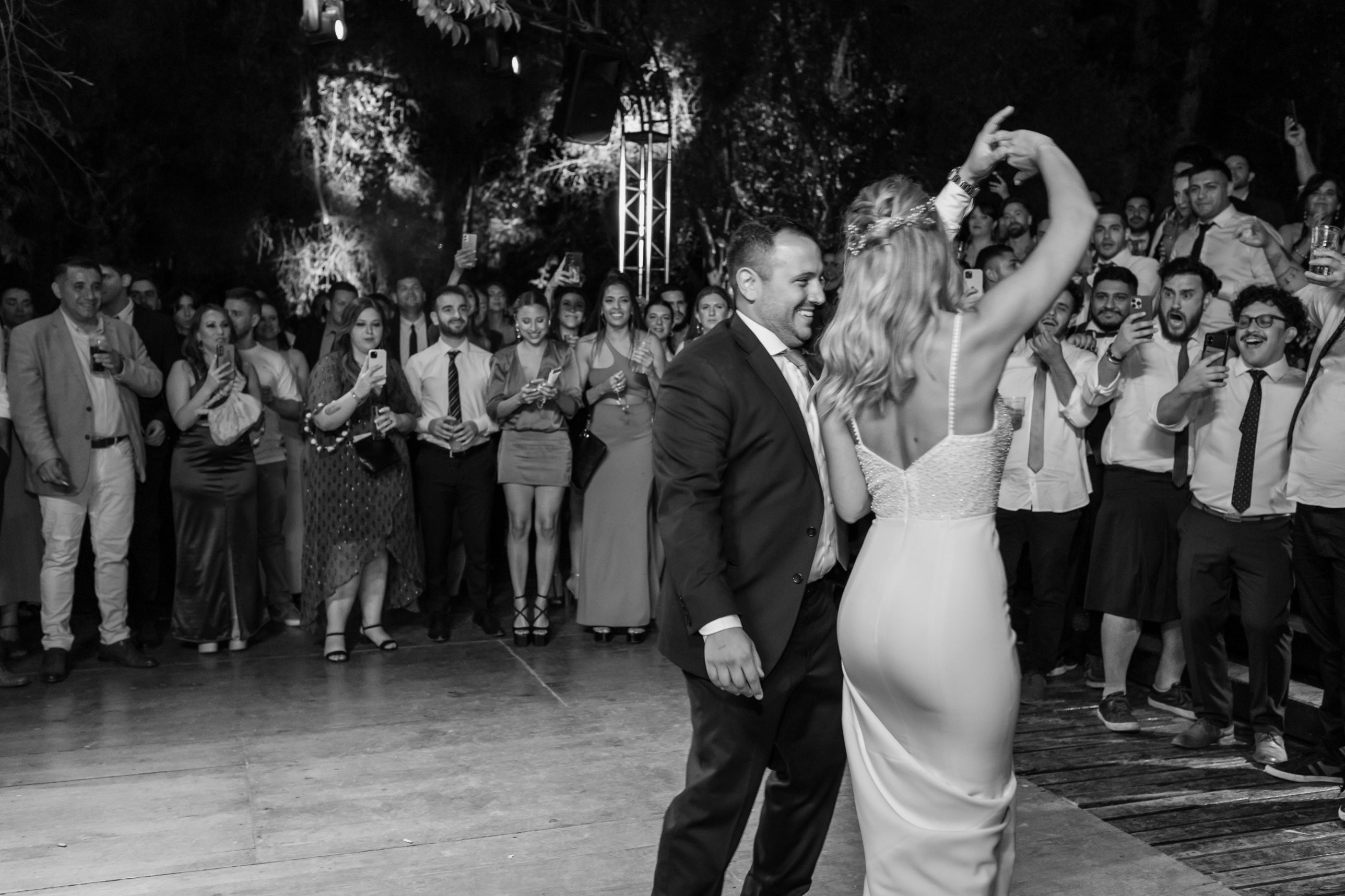 Couple dancing as a crowd of guests cheers around the dance floor